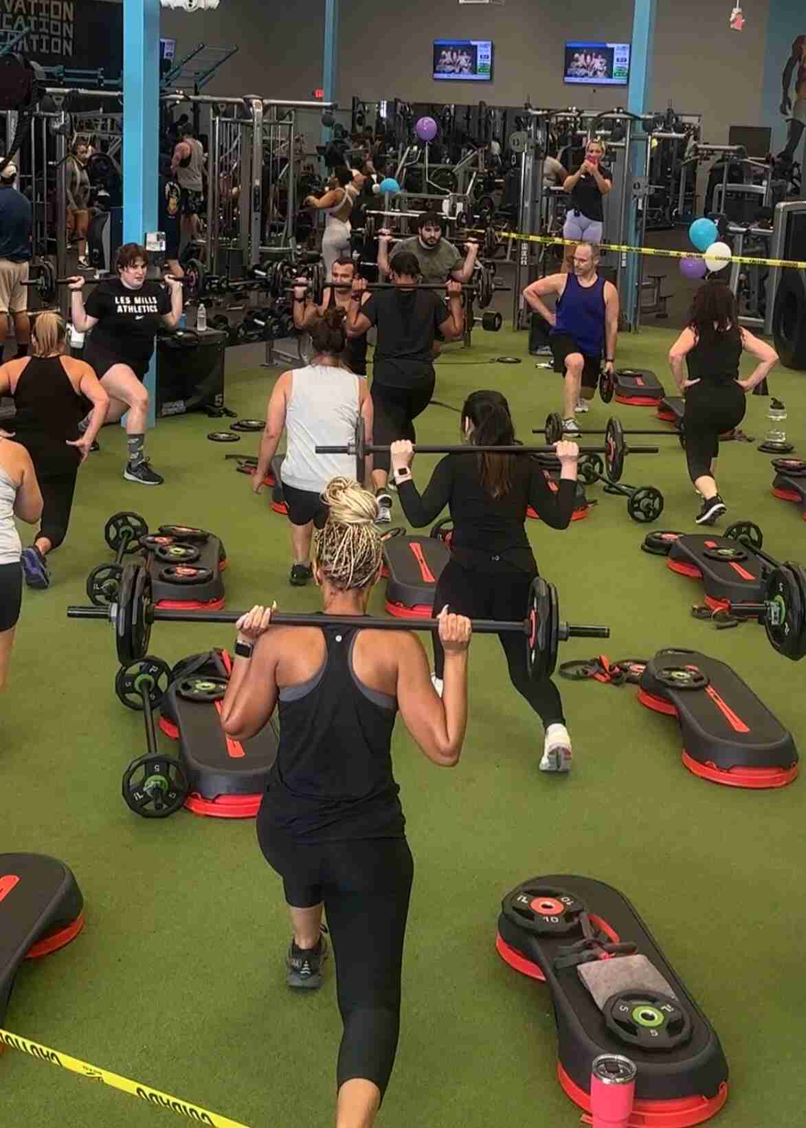 CLUB4 instructor guiding participants through a dynamic workout in a bright studio.