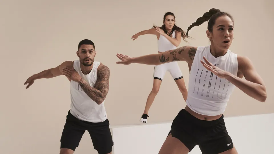 Three people in athletic wear performing a coordinated exercise routine