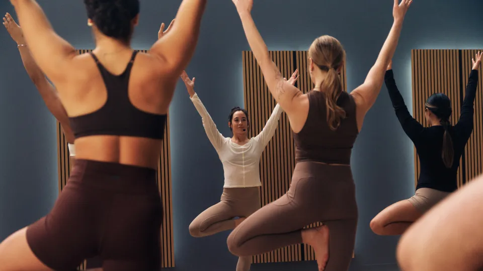 A group of people in a studio performing tree pose